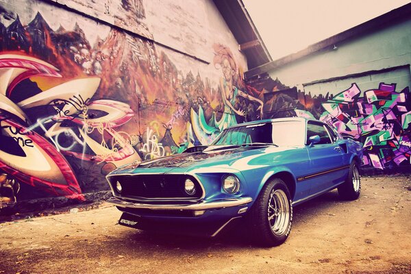 Un Mustang azul de 1969 contra una pared de graffiti