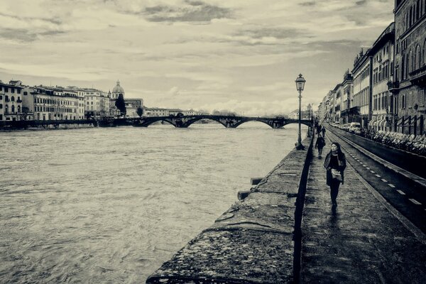 Black and white landscape of the embankment in Florence with passers-by