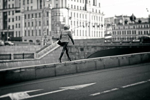 Una chica caminando por el borde de un puente