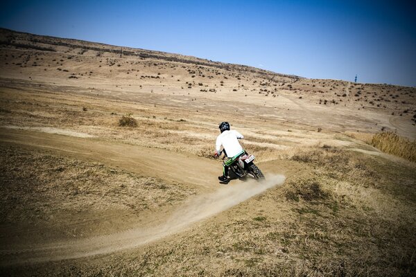 Un motociclista en una moto corre a través de los campos y bosques con seguridad a su señora de un pueblo cercano