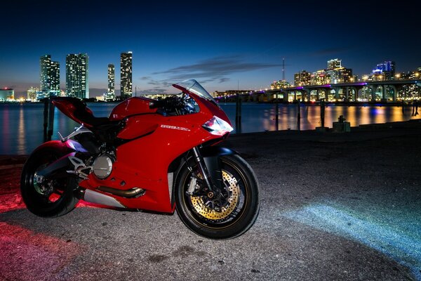 Motocicleta roja en el fondo de la ciudad al atardecer