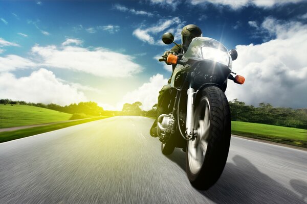 A motorcycle rides on the road against the background of sunset