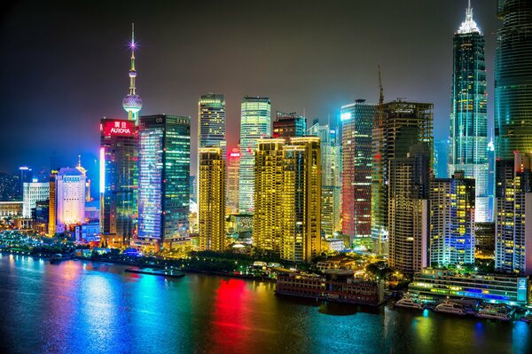 Ночной город Шанхай горит огнями и отражается в реке