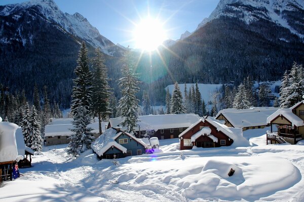 Winterdorf in Schnee vor dem Hintergrund der hellen Sonne gehüllt