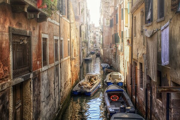 Лодки в канале между домов в Венеции