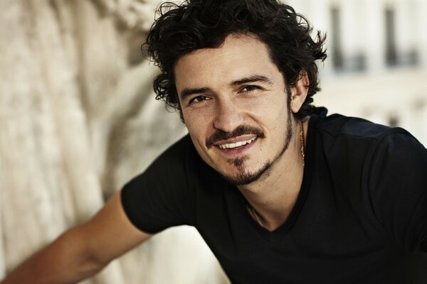 The smile of actor Orlando Bloom. Orlando Bloom in a black T-shirt