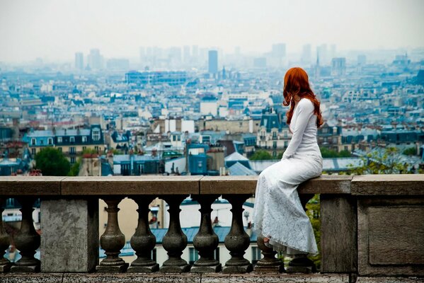 Una chica en la ciudad. Pelirroja chica en un vestido. Vista de París