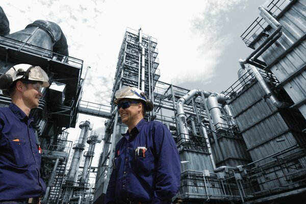 Ingenieure bei der Arbeit. Männer in Uniform vor dem Hintergrund eines Industriegebäudes