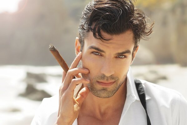 Jeune homme avec un cigare sur fond de mer