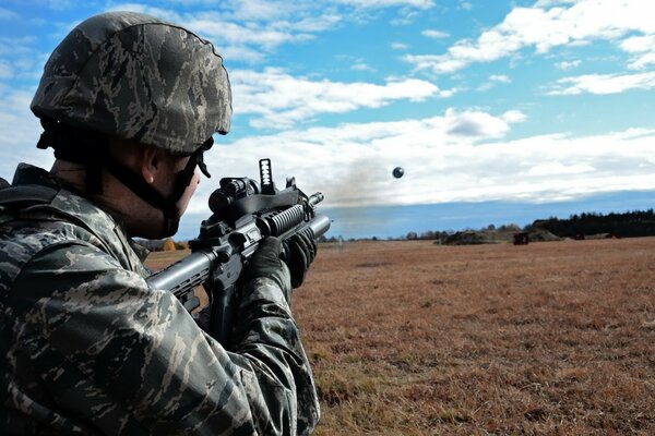 A soldier in uniform shoots with a grenade launcher