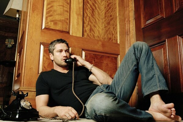 Attore Gerard Butler con il telefono in mano