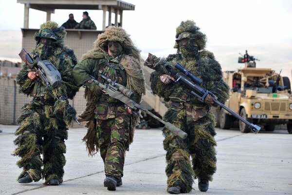 Three soldiers in camouflage with weapons in their hands