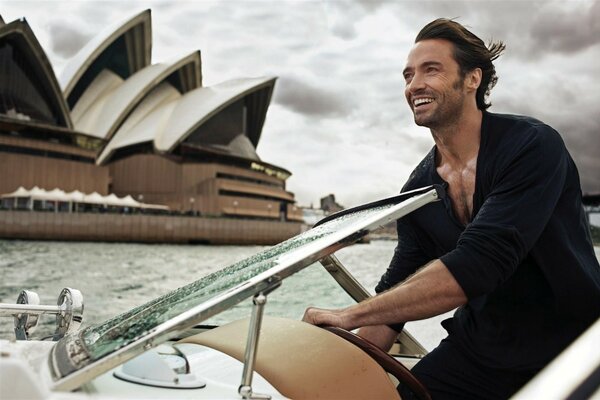 Actor Hugh Jackman in a bathrobe smiles from a boat