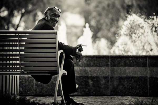 A man with glasses is sitting on a bench