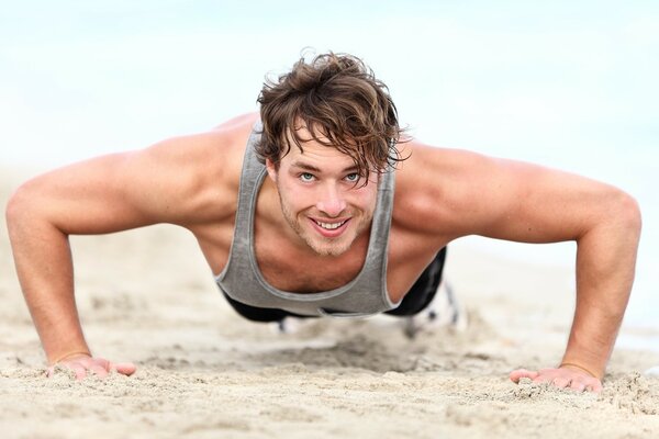 Los músculos de un hombre haciendo flexiones en la arena