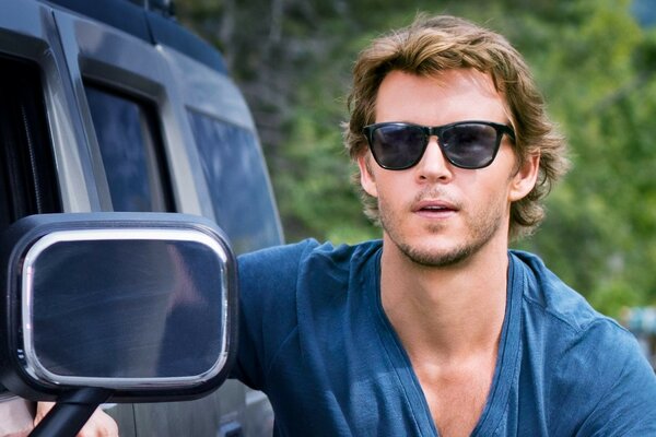 Ryan Kwanten is standing by the car