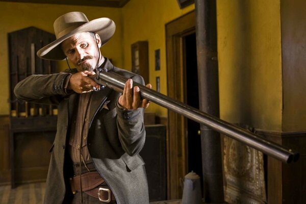 A man in a cowboy hat with a gun