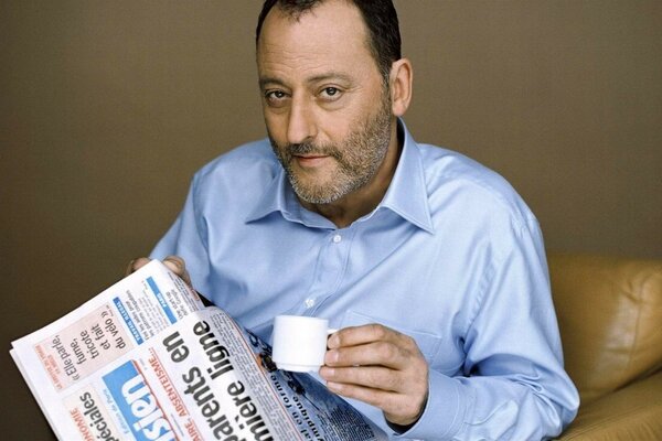 El actor francés Jean Reno Lee el periódico con una taza de café