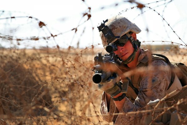 Soldat mit Waffen hinter Stacheldraht