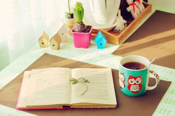 Ein gemütlicher Tisch, auf dem ein offenes Buch und eine Tasse Tee liegen