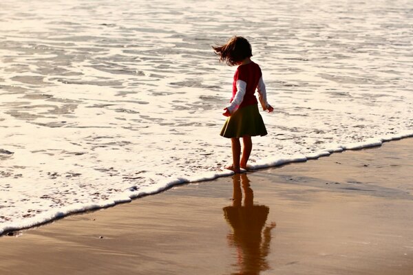 Ragazza bagna i piedi in acqua sulla spiaggia