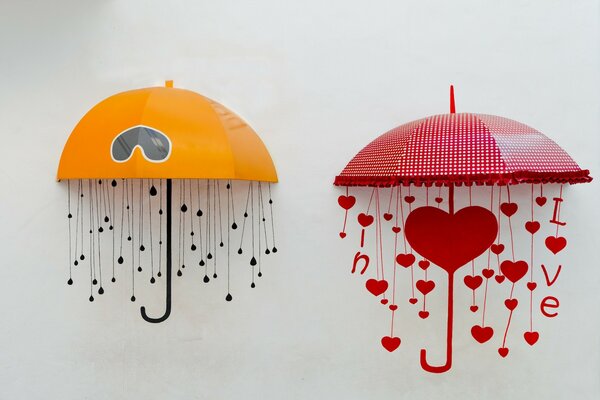 A yellow umbrella with a black handle and a red umbrella with hearts on a white wall