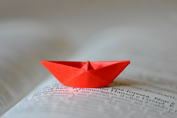 Un bateau en papier rouge se trouve sur les feuilles d un livre ouvert