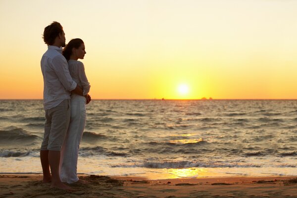 Coppia che guarda il tramonto in riva al mare