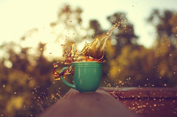 Café éclaboussé dans une tasse verte sur fond de nature