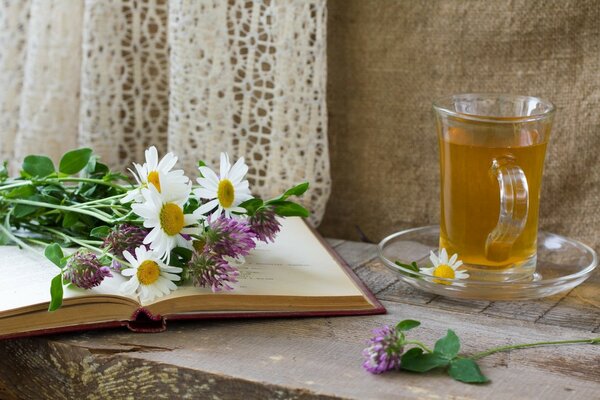 Taza de té en la mesa con flores en el libro