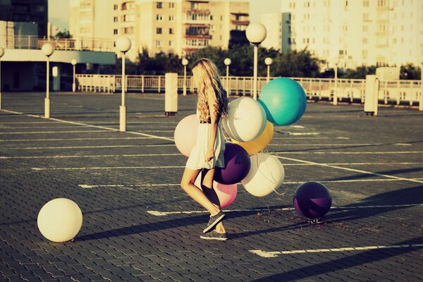 Ein Mädchen geht die Straße entlang und hält einen Haufen Luftballons in der Hand