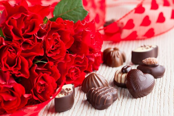 Dulces de chocolate con un ramo de rosas rojas