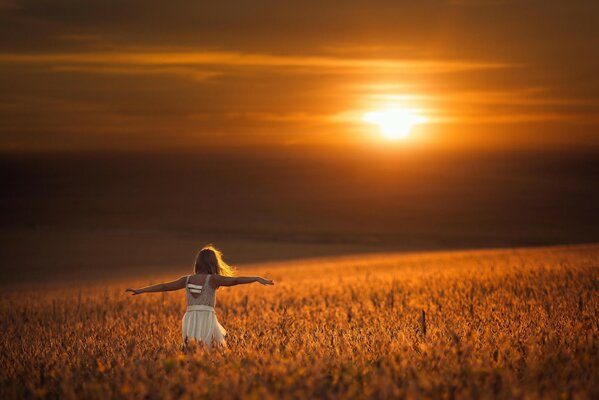 A girl in the rays of the sun is spinning in a field