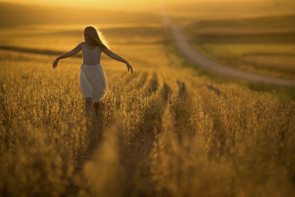 Una niña corre por el campo en los rayos del atardecer