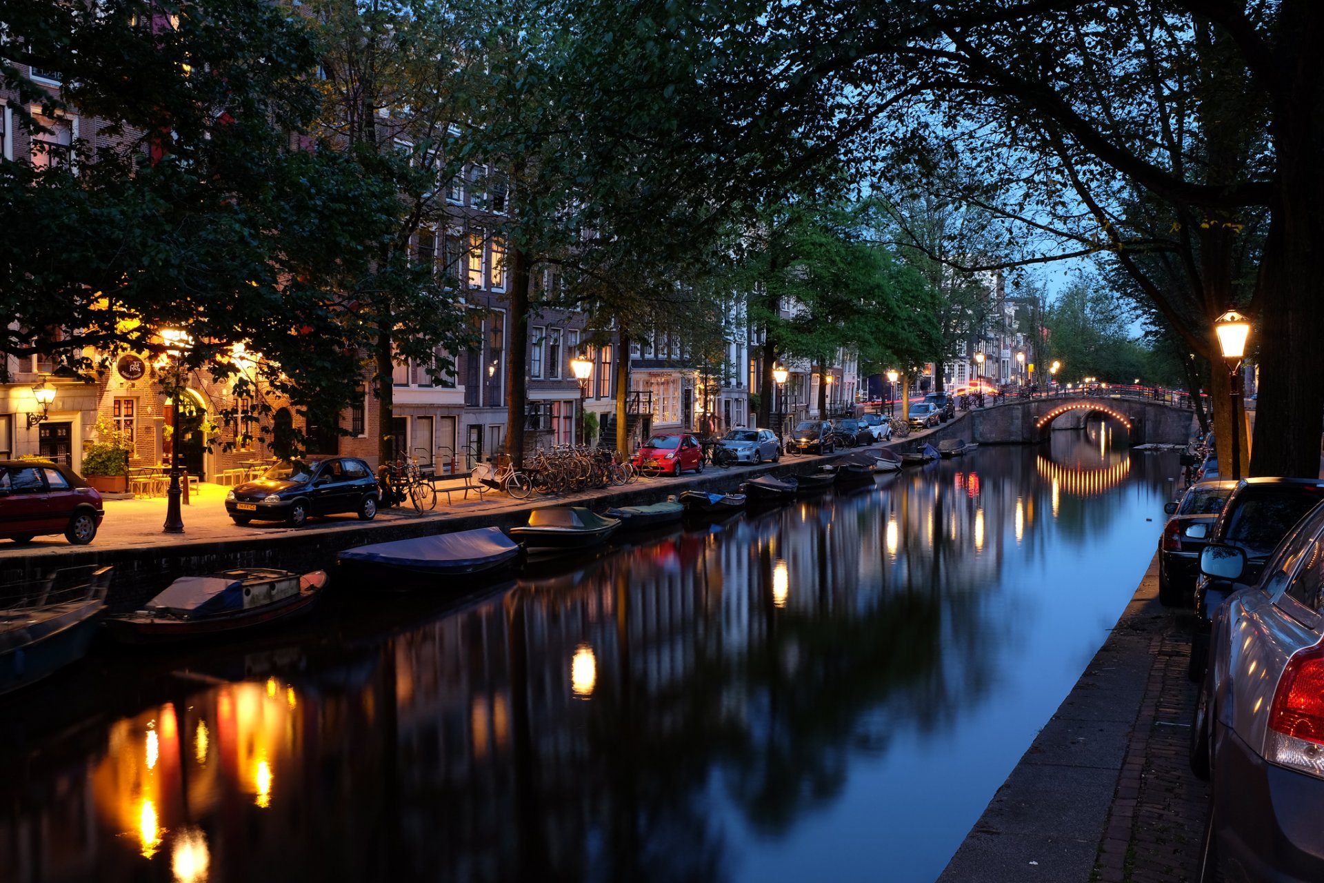 amsterdam niederlande stadt abend brücke kanal fluss boote autos häuser lichter beleuchtung bäume