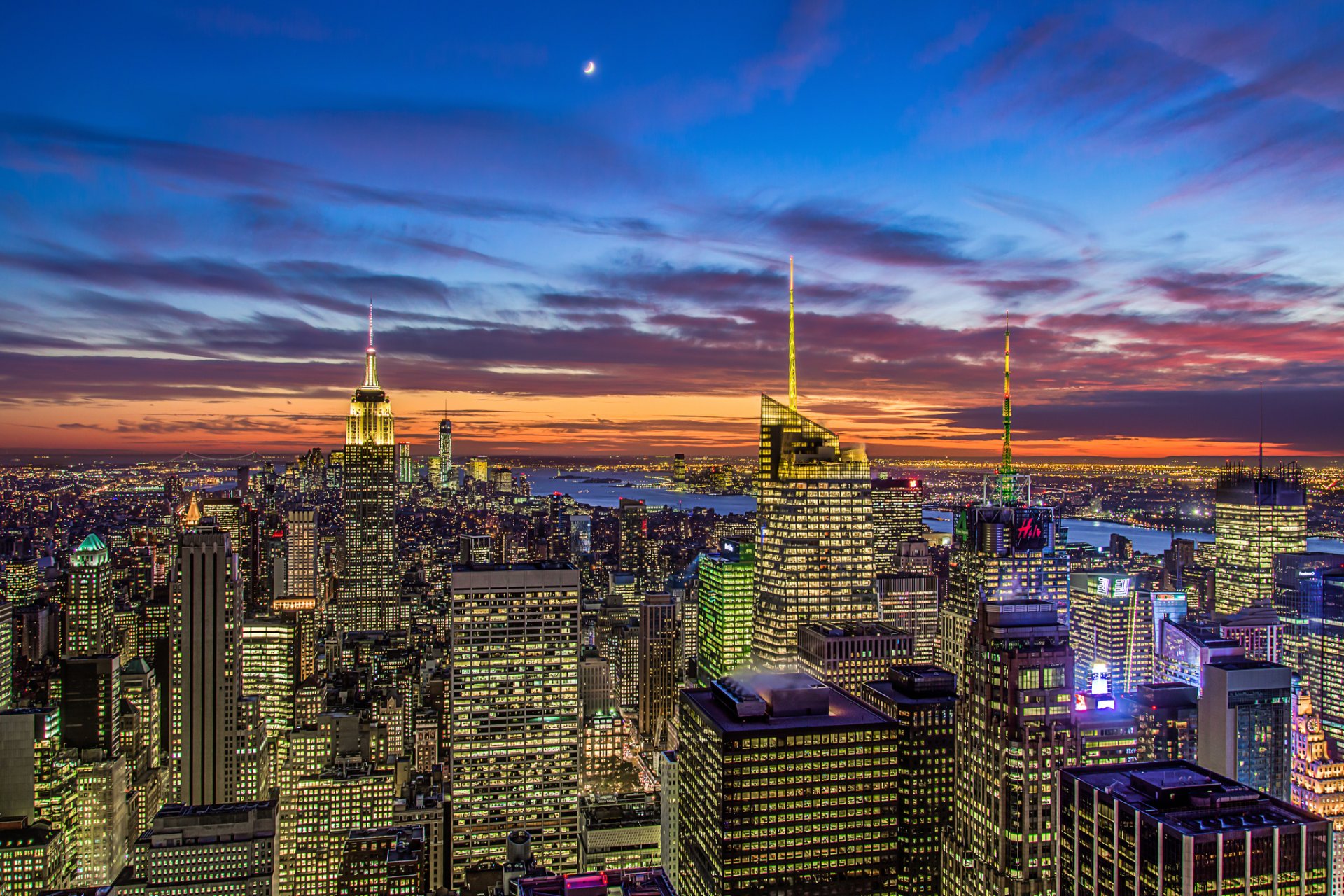 new york stati uniti manhattan empire state building quartiere dei teatri empire state building città panorama sera vista grattacieli edifici case grattacieli luci arancione tramonto blu cielo nuvole luna mese