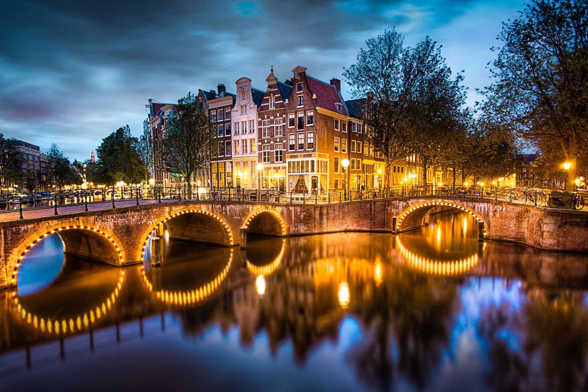 amsterdam niederlande stadt abend himmel wolken kanal brücke lichter beleuchtung fluss wasser reflexion häuser straßen laternen bäume