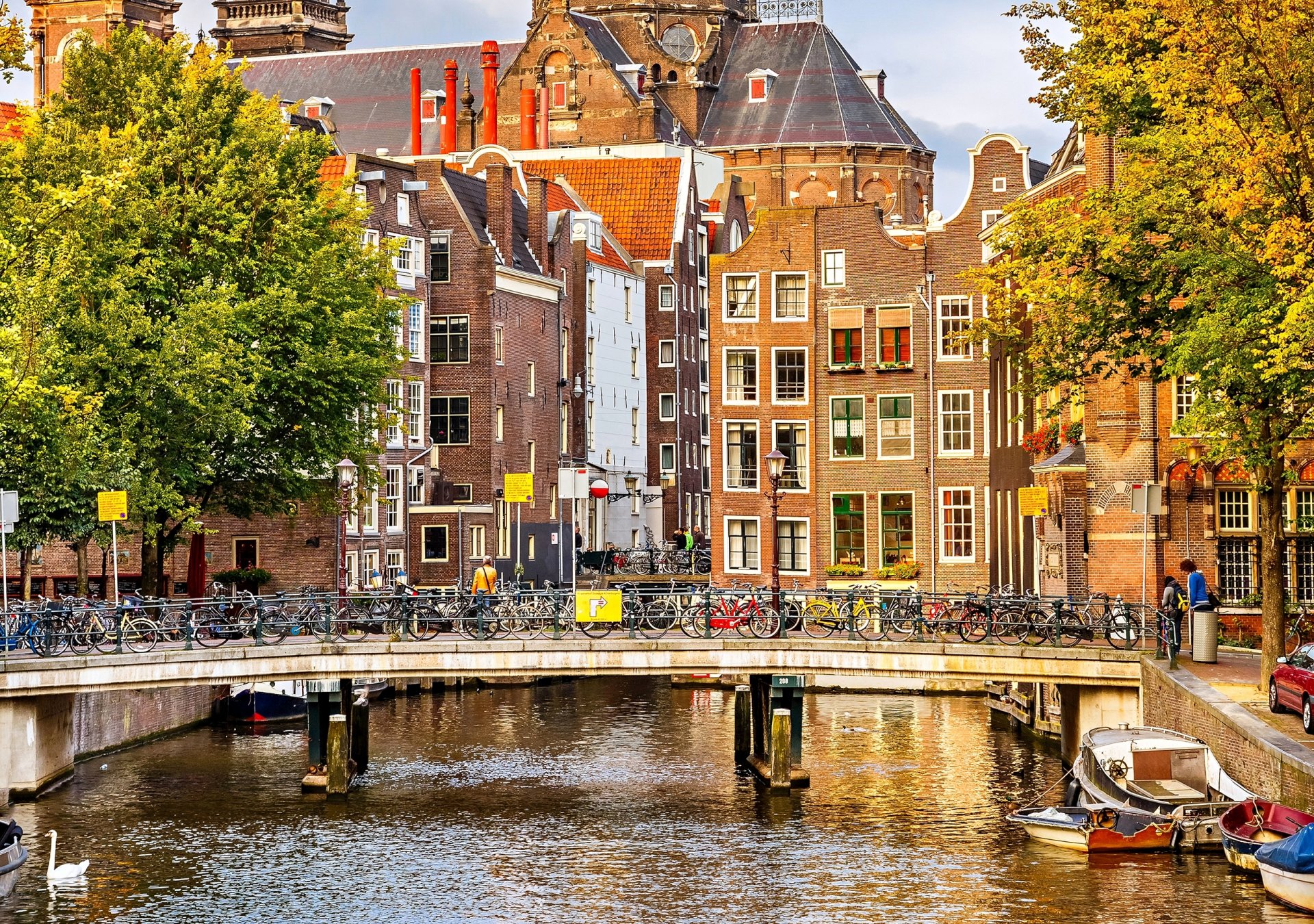 amsterdam netherlands autumn trees city houses buildings architecture bridge bicycles canal river boats people