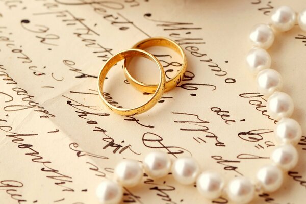 Wedding rings and pearls on the letter