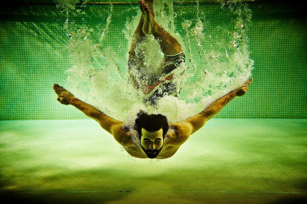 Homme sportif plonge dans la piscine