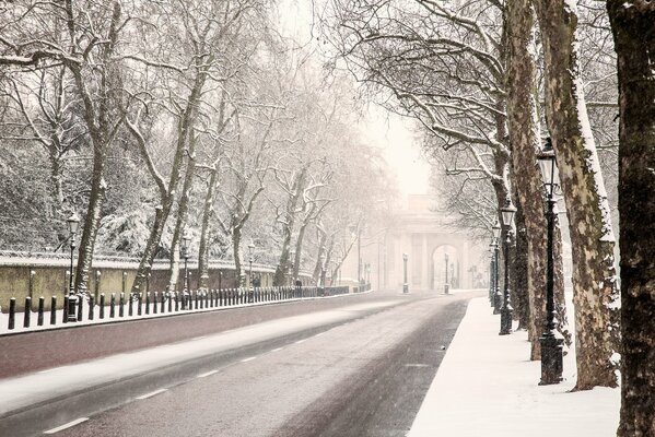 English winter road among the trees going towards the arch with lanterns