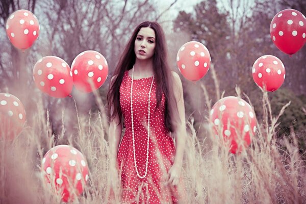 A charming girl in a polka dot dress is standing near the same balls