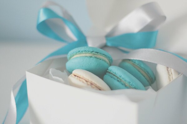 Biscuits bleus et blancs dans une boîte blanche avec ruban bleu et blancet sur fond blanc