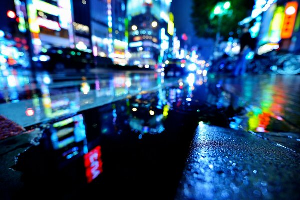 Odbicie nocnej Japonii na mokrym asfalcie