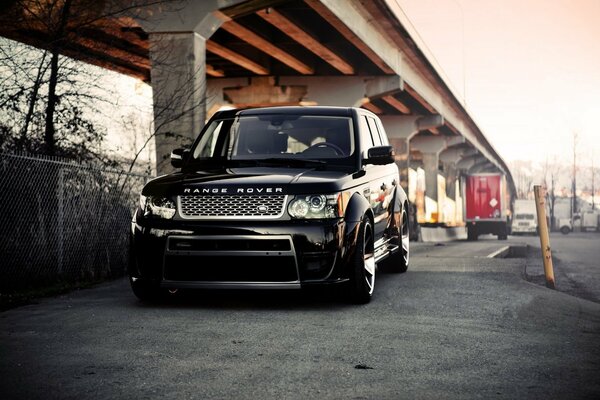 Black handsome range rover on the street under the bridge