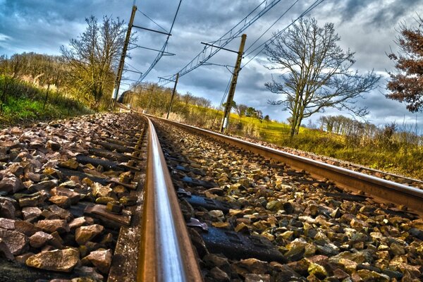 Les rails partent au loin par temps nuageux