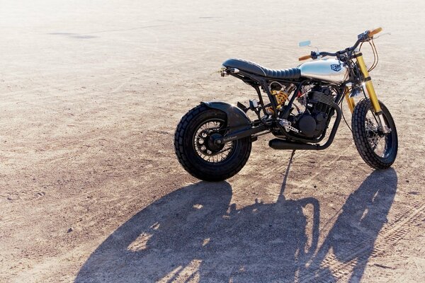 The motorcycle is standing on the sand