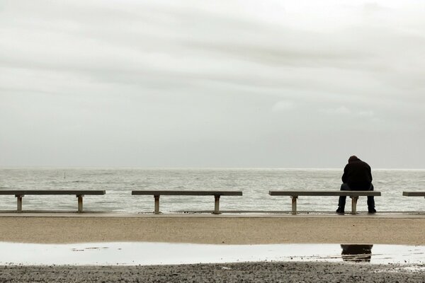 Homme assis seul au bord de la mer sur un banc