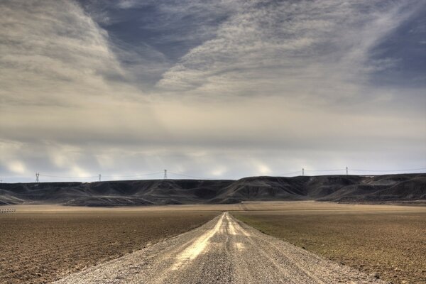 El largo camino en el desierto, las nubes y el camino