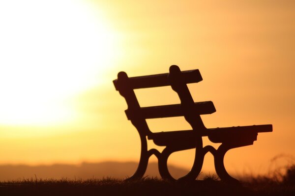 Silueta de banco contra el fondo de una puesta de sol naranja